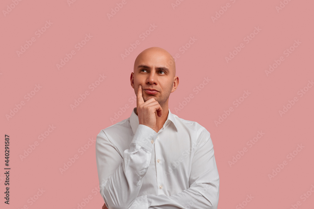 Gifts or vacation. Serious brooding bald man in white shirt holds chin ...