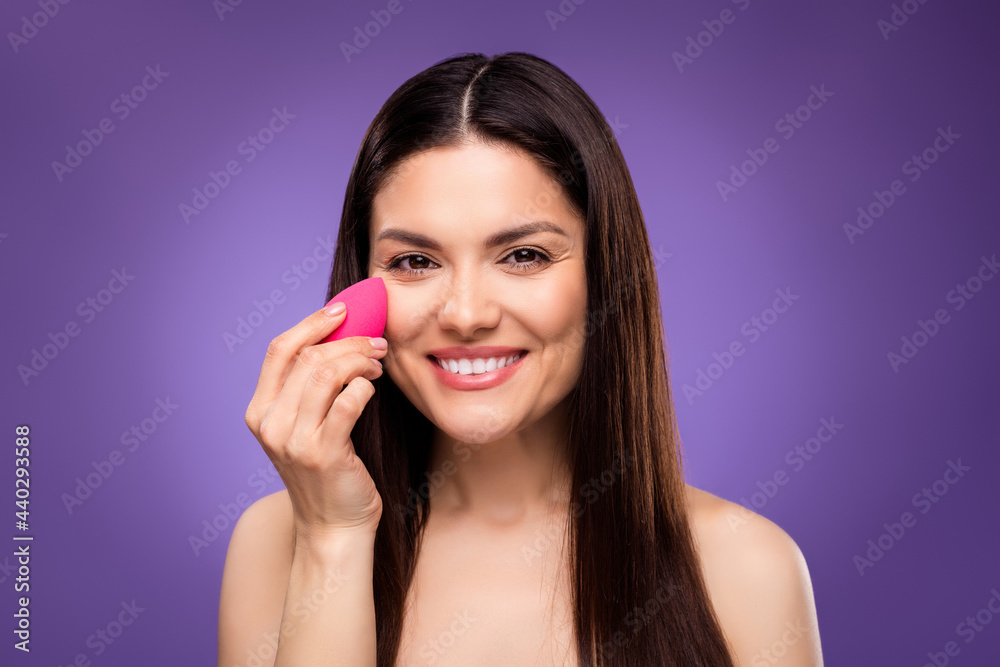 Photo of dreamy charming young lady wear nothing applying foundation beauty blender smiling isolated purple color background Photo of dreamy charming young lady wear nothing applying foundation beauty blender smiling isolated purple color background