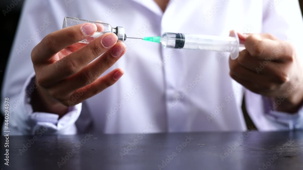 Close up. The hands of a female doctor holds a jar with a vaccine in her hand and collects a medicine with a syringe Close up. The hands of a female doctor holds a jar with a vaccine in her hand and collects a medicine with a syringe