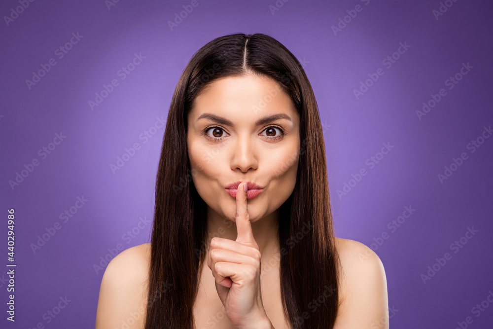 Portrait of attractive mysterious woman showing shh sign isolated over bright violet purple color background Portrait of attractive mysterious woman showing shh sign isolated over bright violet purple color background