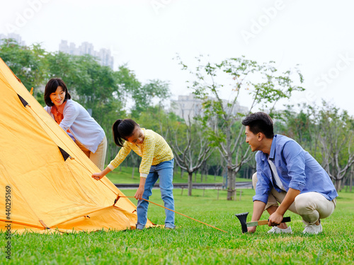 A happy family of three set up tents outdoors