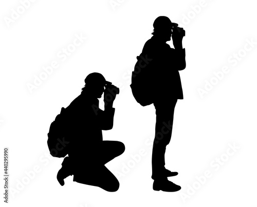Outdoor Landscape Photographer Silhouette. Sitting and standing man with backpack taking photos.