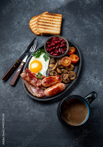 English Breakfast with fried eggs, sausages, bacon, beans, toasts, tomatoes and mushrooms
