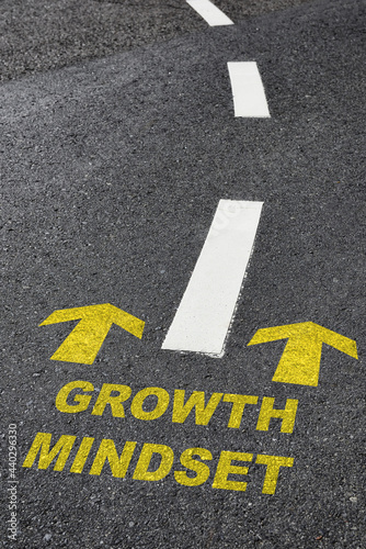 Growth mindset with yellow arrow marking on road surface with white marking line. Optimism empathy personality concept and motivation to success idea