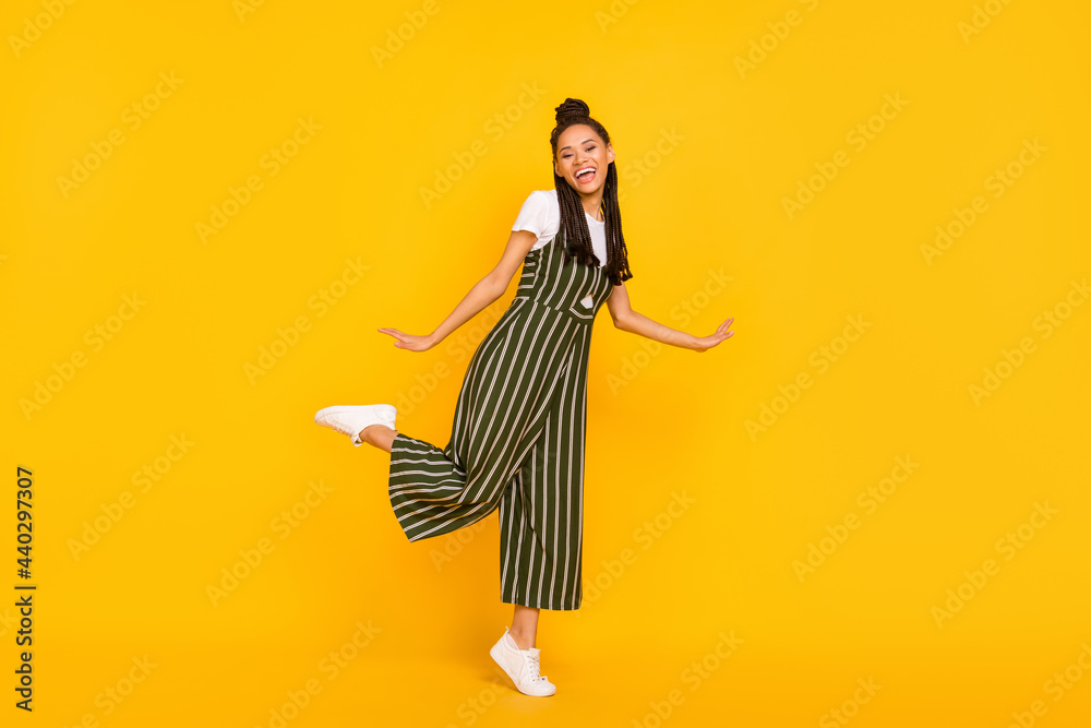 Full length photo of adorable pretty dark skin lady wear striped clothes dancing smiling isolated yellow color background Full length photo of adorable pretty dark skin lady wear striped clothes dancing smiling isolated yellow color background