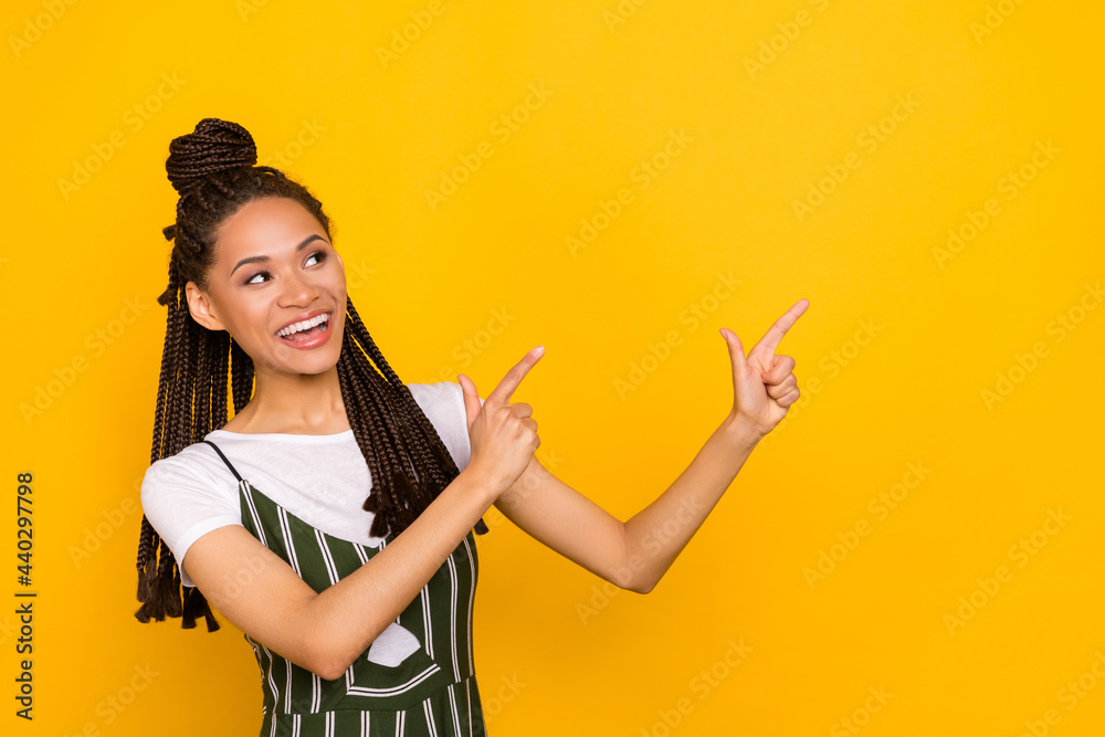 Photo of young black girl happy positive smile indicate finger empty space advertise decision isolated over yellow color background Photo of young black girl happy positive smile indicate finger empty space advertise decision isolated over yellow color background