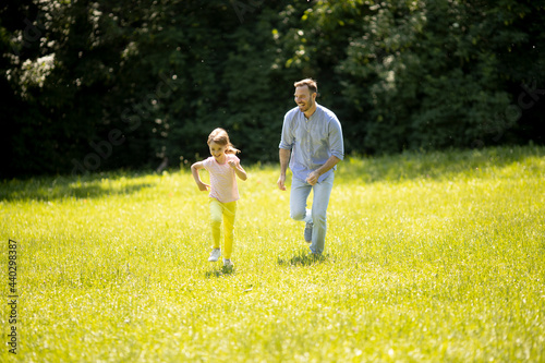 Fotografie Father chasing his little daughter while playing in the park