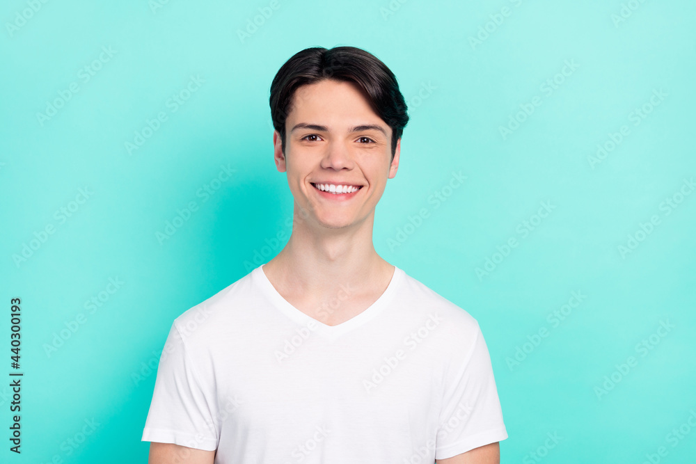 Photo of optimistic brunet hairdo teenager guy wear white t-shirt isolated on bright teal color background Photo of optimistic brunet hairdo teenager guy wear white t-shirt isolated on bright teal color background