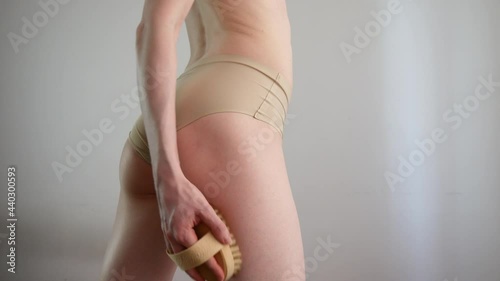 young woman makes herself an anti-cellulite massage with a dry brush