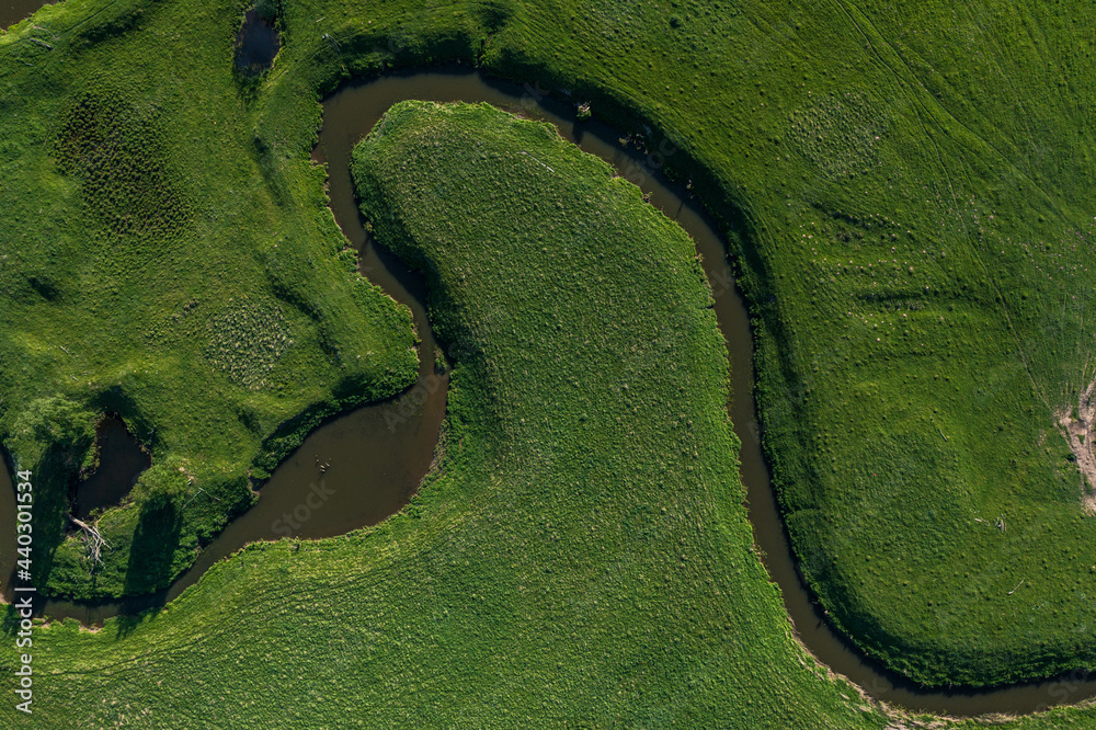 aerial landscape of winding river in green field, top view of beautiful nature texture from drone. High quality photo