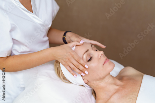 Face massage. Close-up of adult woman getting spa massage treatment at beauty spa salon. Spa skin and body care. Facial beauty treatment. Cosmetology.