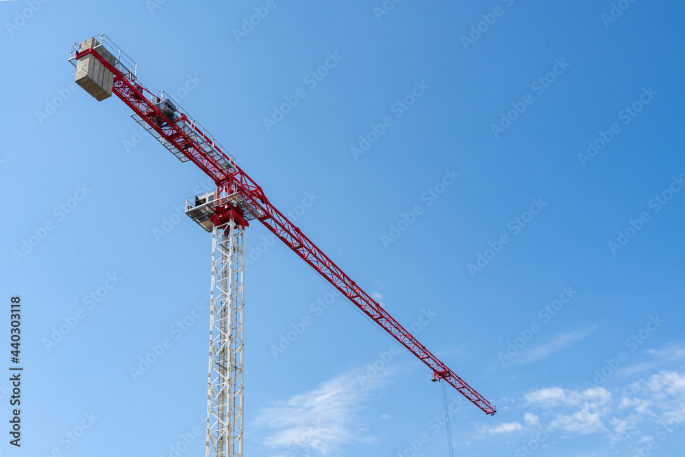 red and white construction crane on a blue sky background. The building of the new houses and construction of buildings in the city. red and white construction crane on a blue sky background. The building of the new houses and construction of buildings in the city.