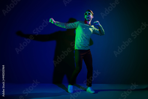 Full size photo of young man happy positive smile excited dance music nightclub party isolated over dark color background