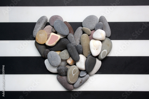 A heart made of sea pebbles on a striped background.