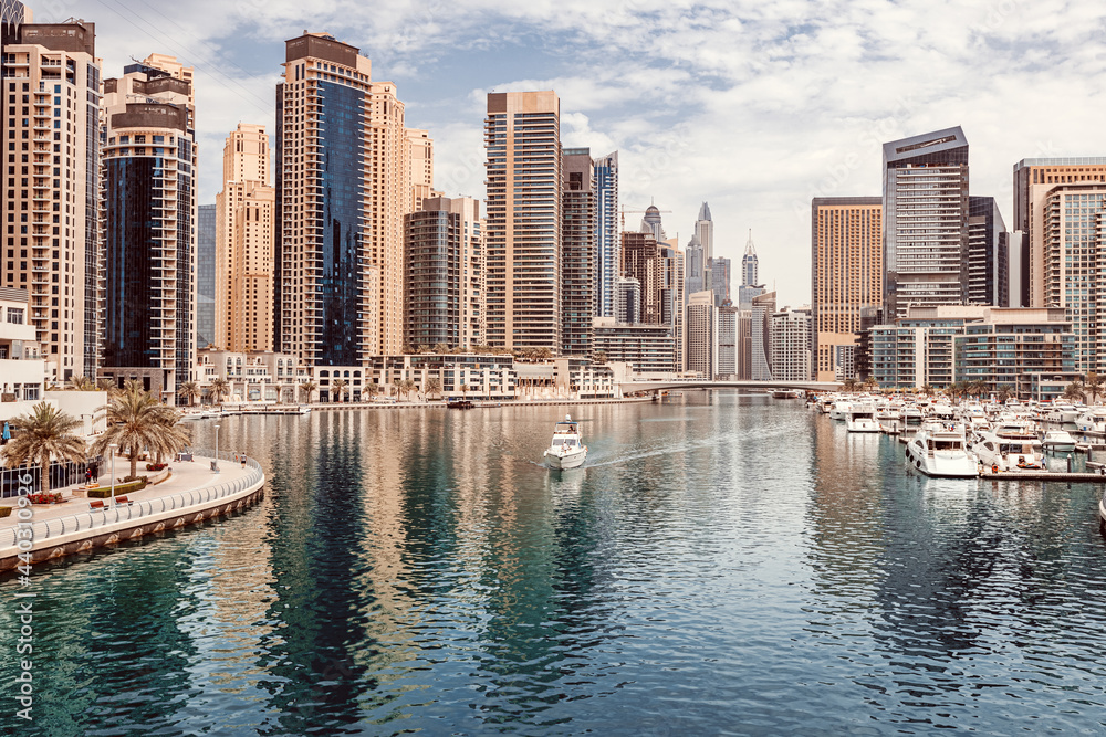 Fototapeta premium The boat sails along the canal in the Dubai Marina area against the backdrop of numerous residential skyscrapers and hotels