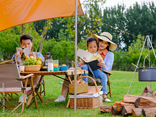 A happy family of three reading outside