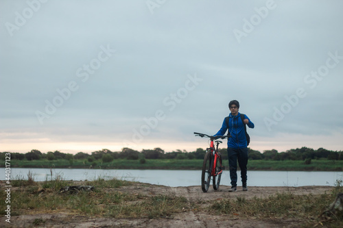 Young man with headphones walking with his bike next to him
