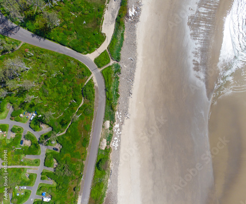 In the photo we see the ocean shore, the coastal green area, as well as the highways. There are no people in the photo. There is an empty space for your insert. View from above. Aerial photography.