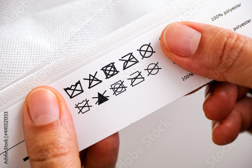 Woman hands holding label with cleaning instructions of polyester thing photo