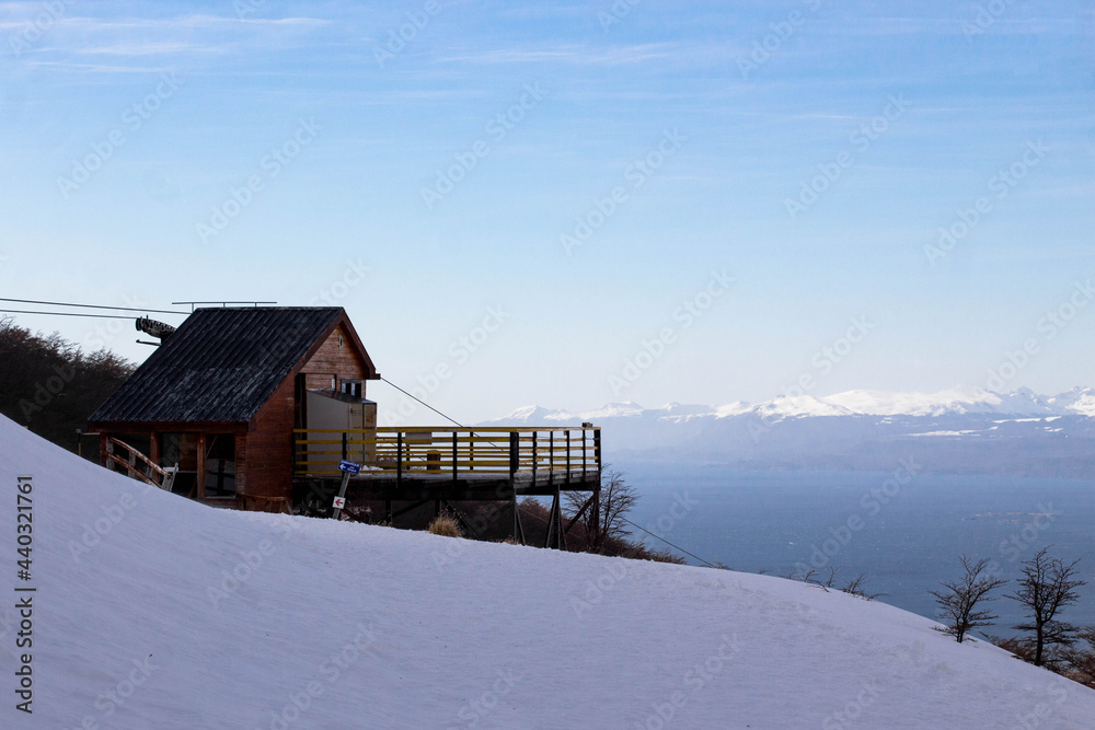 CERRO MARTIAL, USHUAIA, ARGENTINA - SEPTEMBER 06, 2017: Lift shed sits at the top of snow-covered Cerro Martial, Ushuaia, in the end of winter. Beagle canal can be viewed in the background.