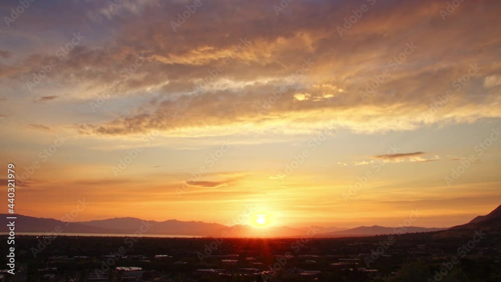 Timelapse of the sun setting over Utah Valley looking over Orem as it fades behind the mountains.