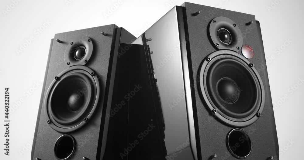 Music speakers with piano lacquer body and vibrating bass woofer membrane slowly turning around on white background Music speakers with piano lacquer body and vibrating bass woofer membrane slowly turning around on white background