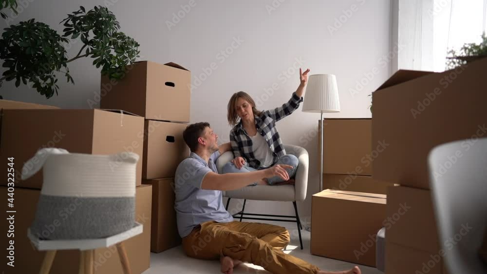 Happy young family discusses a plan for a new home immediately after relocation. Husband and wife sit among cardboard boxes Happy young family discusses a plan for a new home immediately after relocation. Husband and wife sit among cardboard boxes