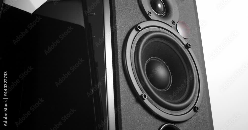 Music speakers with piano lacquer body and vibrating bass woofer membrane slowly turning around on white background Music speakers with piano lacquer body and vibrating bass woofer membrane slowly turning around on white background