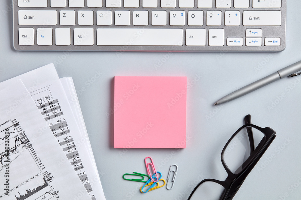 Office workspace desktop with a blank pink note paper in the middle. Office workspace desktop with a blank pink note paper in the middle.