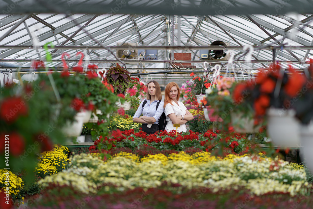 Two women posing in a greenhouse between hundreds of flowers Two women posing in a greenhouse between hundreds of flowers