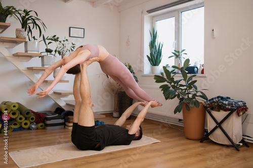 Young couple practicing acro yoga together at home in a modern interior. Hobby, togetherness, healthy lifestyle photo