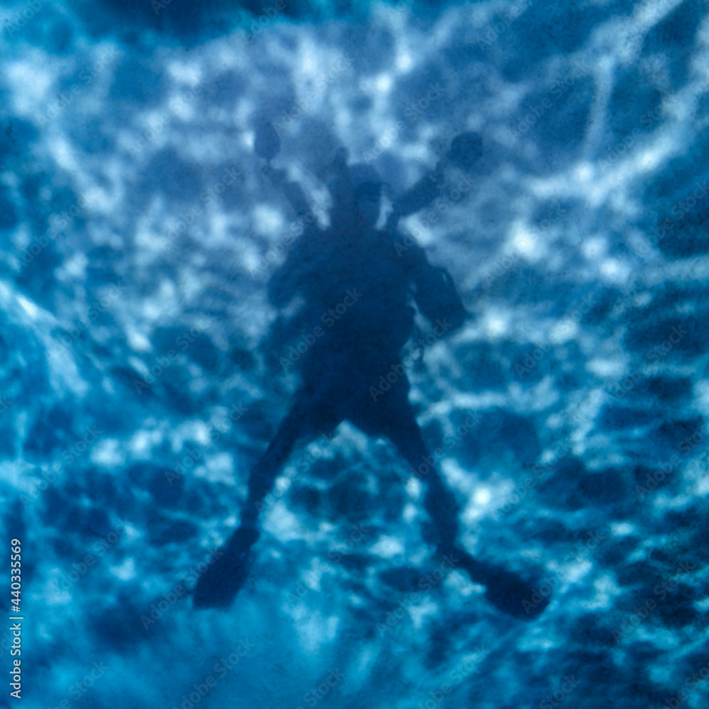 Underwater selfie, silhouette against sandy bottom with sunlight in the back of the diver, in Maldives