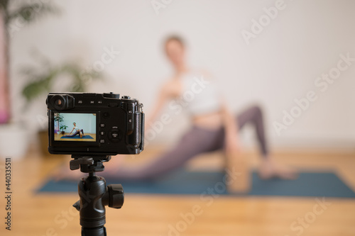 Sporty young woman doing yoga practice on white wall background with plants - concept of healthy life and natural balance between body and mental development