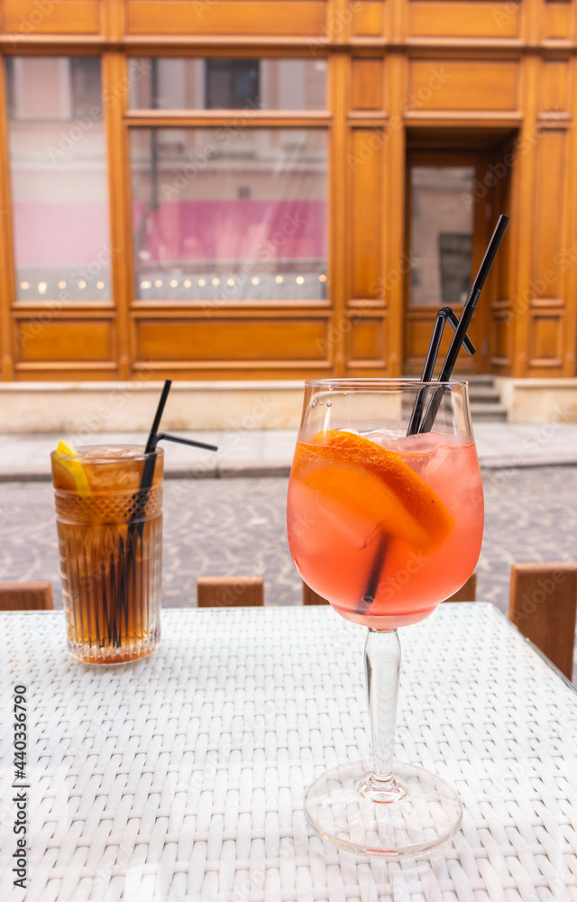 Long Island cocktail and Spritz Aperol with straws on table. Mixed alcoholic cocktails on table