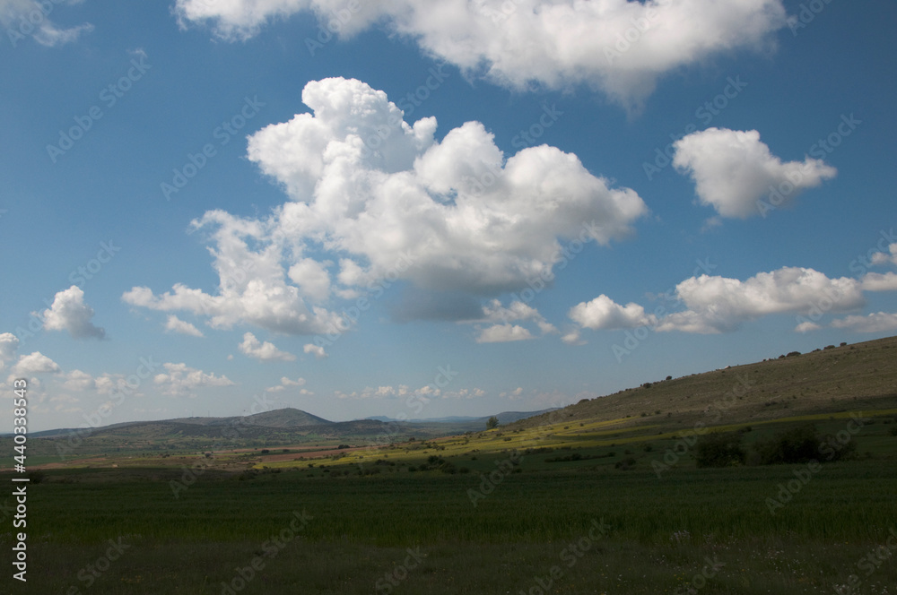 Beautiful landscape with hills, green fields and blue sky with white clouds. Soria, Spain, Europe