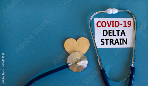 New Covid-19 delta strain symbol. White card, words 'Covid-19 delta strain' and stethoscope, blue background. Wooden heart. Medical and covid-19 delta strain concept, copy space.