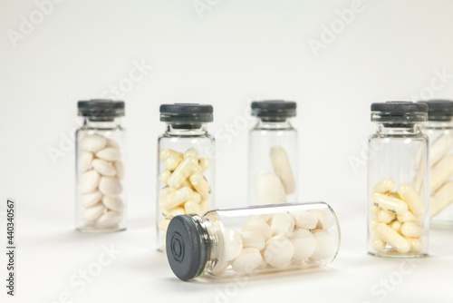 Set of pills on cristal jar for vaccines on coloured background