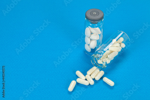 Set of pills on cristal jar for vaccines on coloured background