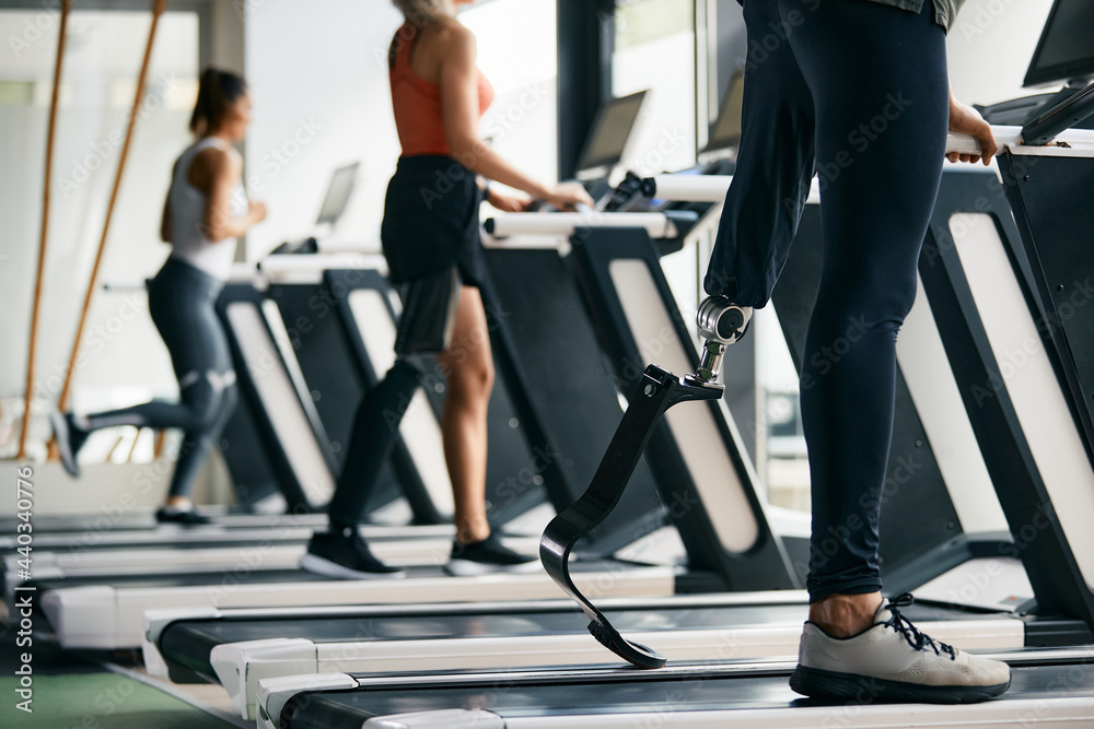 Close-up of sportsman with artificial leg walks on treadmill while working out at gym. Close-up of sportsman with artificial leg walks on treadmill while working out at gym.