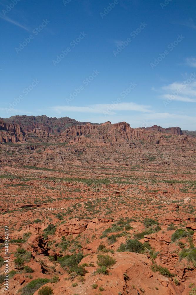 The steep canyon. Panorama view of the red desert, cliffs, orange sandstone formations and rocky mountains in the horizon in Sierra de las Quijadas national park in San Luis, Argentina.