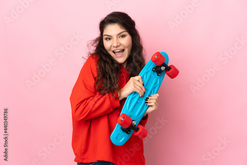 Teenager Russian girl isolated on pink background with a skate with happy expression