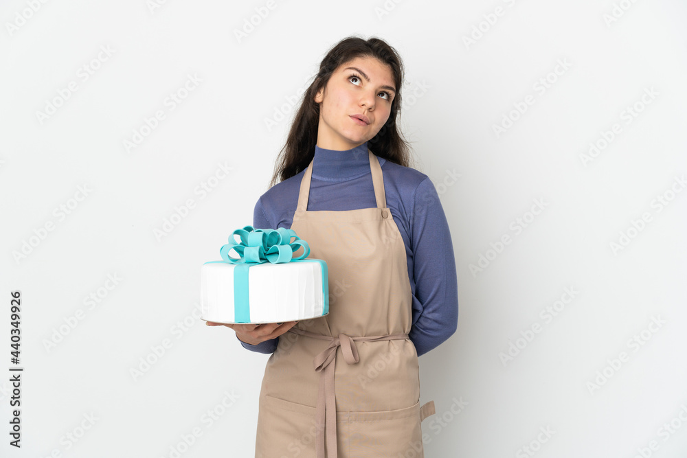 Pastry Russian chef holding a big cake isolated on white background and looking up Pastry Russian chef holding a big cake isolated on white background and looking up