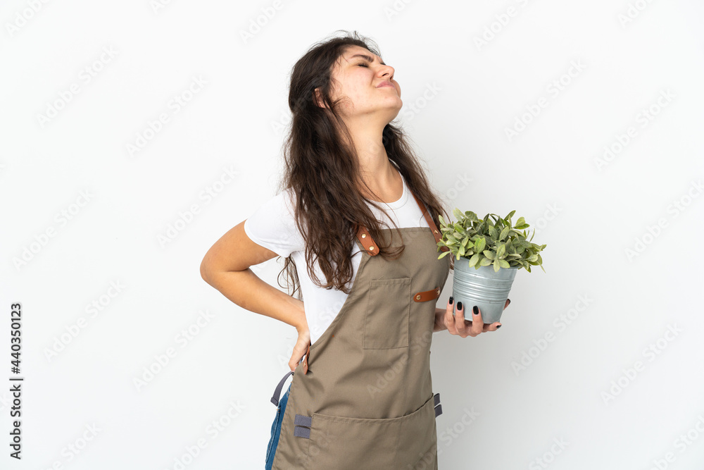 Young Russian gardener girl holding a plant isolated suffering from backache for having made an effort Young Russian gardener girl holding a plant isolated suffering from backache for having made an effort