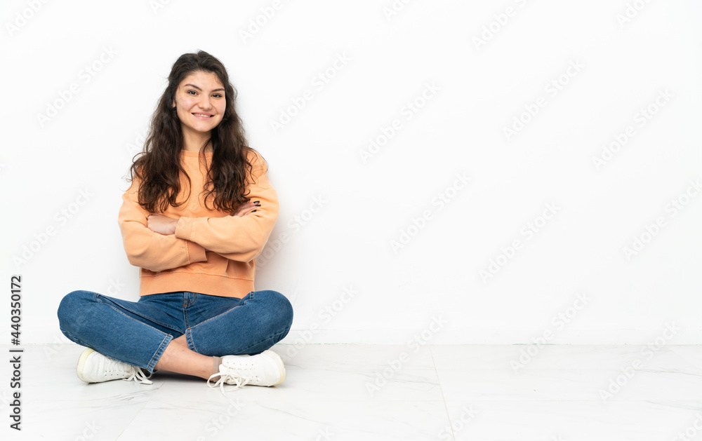 Teenager Russian girl sitting on the floor keeping the arms crossed in frontal position Teenager Russian girl sitting on the floor keeping the arms crossed in frontal position