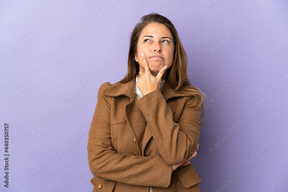 Middle age Brazilian woman isolated on purple background having doubts Middle age Brazilian woman isolated on purple background having doubts