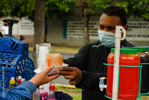 Hispanic street seller in a colorful food cart selling sweet ice desserts photo
