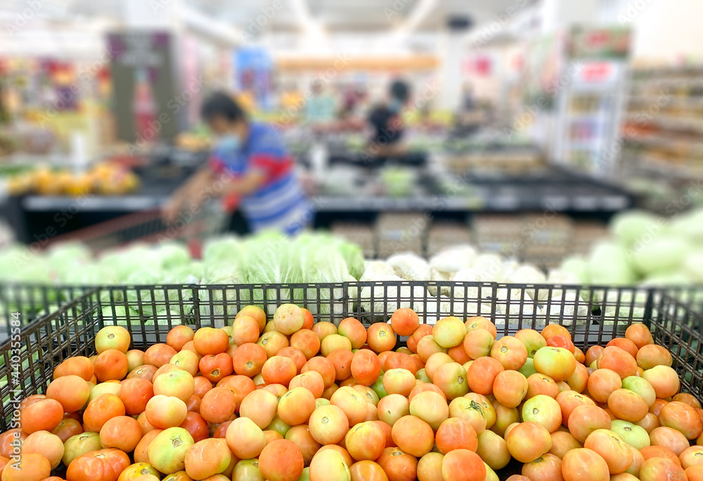 Shopping inside supermarket grocery section, defocused. Selective focus on tomatoes.