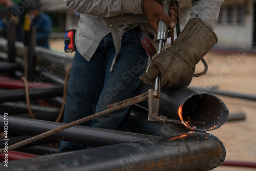 blacksmith working in a workshop welder use gass cutting iron pipe in the workside in factory photo