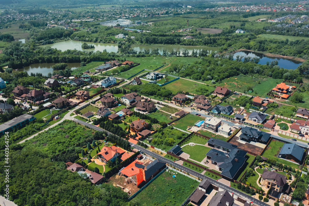 Turtle roofs of luxury houses and cottages in a natural landscape park near the city - aerial drone shot. The roofs of luxury cottages and houses are a concept of Luxury neighborhood. 