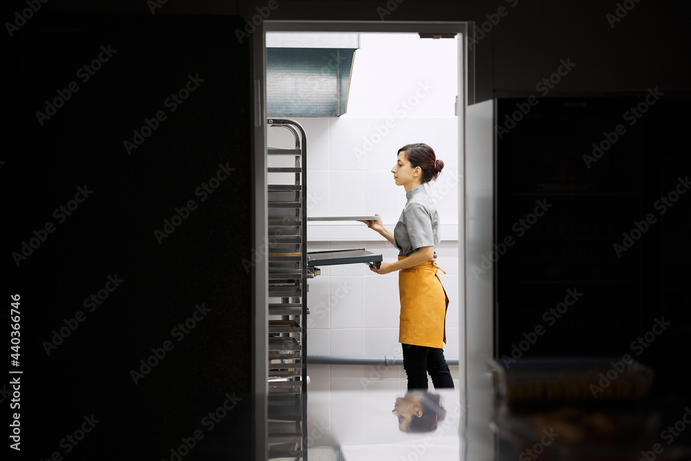 The pastry chef checks the readiness of the dish in the oven The pastry chef checks the readiness of the dish in the oven